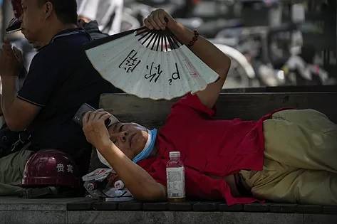 Un Hombre se protege del calor con un abanico en Beijing, China. Foto: Andy Wong, AP Photo