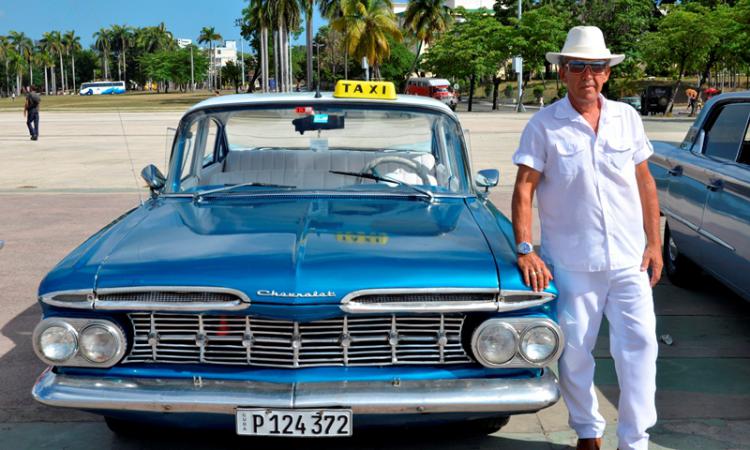 Miembro del Club de Autos Antiguos de Santiago de Cuba, al lado, un Chevrolet Impala del 59 Autos antiguos continúan “pidiendo vía” en Santiago de Cuba